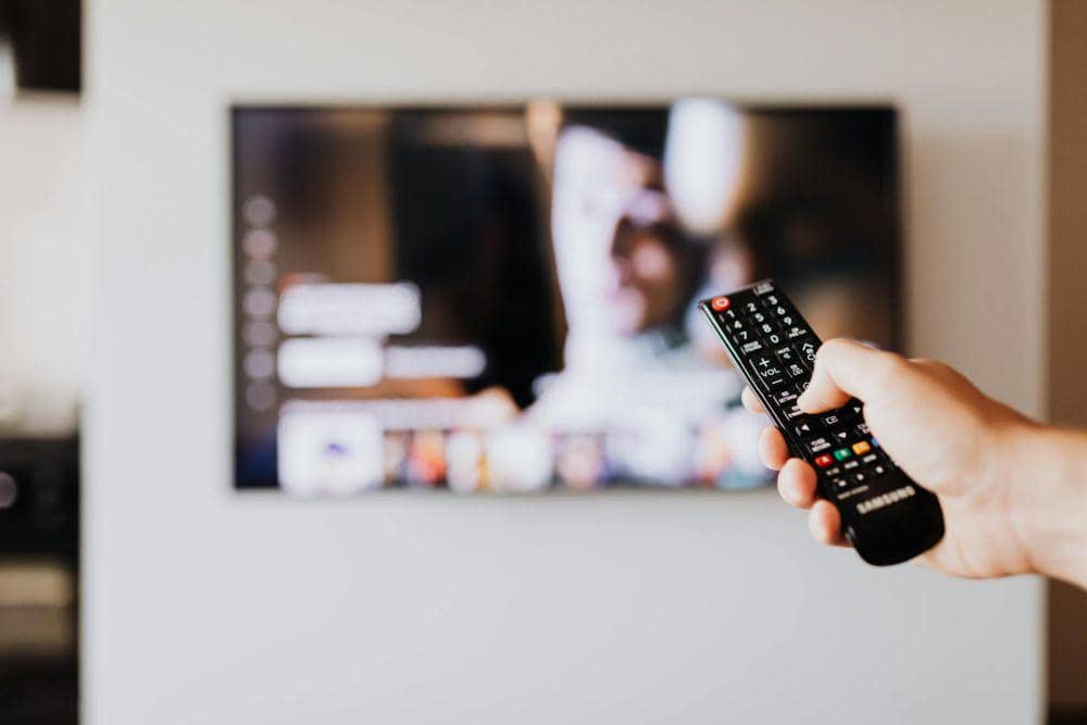 ilustrasi seseorang memegang remote TV (pexels.com/Photo By: Kaboompics.com)