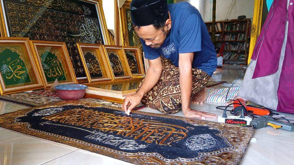 Komarudin mengerjakan pesanan kaligrafi. IDN Times/ Bramanta Pamungkas