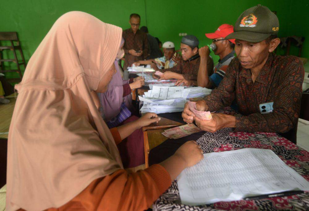 Warga menunjukan uang tunjangan hari raya (THR) yang diberikan oleh pemerintah desa di Kantor Desa Wunut, Tulung, Klaten, Jawa Tengah, Selasa (18/3/2025). (ANTARA FOTO/Aloysius Jarot Nugroho)