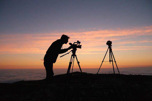 ilustrasi siluet seseorang sedang menggunakan tripod untuk memotret benda langit (unsplash.com/KOBU Agency)