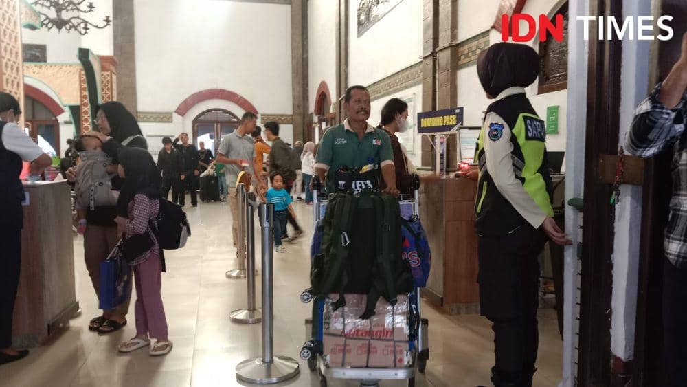 Seorang potter mendorong troli berisi barang bawaan penumpang kereta api di Stasiun Tawang Semarang. (IDN Times/Fariz Fardianto)
