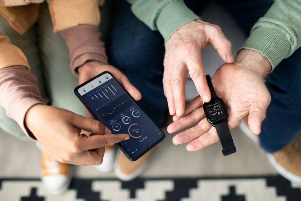 Dua orang memegang ponsel dengan aplikasi kebugaran dan jam tangan pintar hitam yang menampilkan data aktivitas fisik.