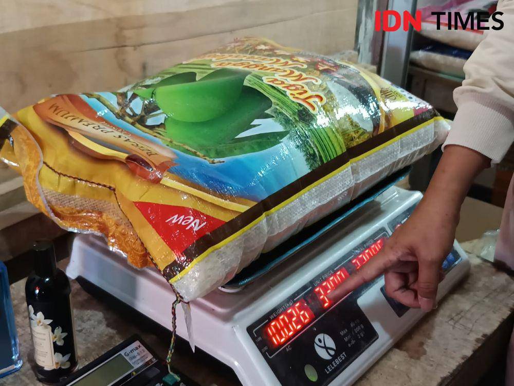 Pedagang menunjukkan hasil timbangan beras Tiga Mangga Manalagi kemasan 10 kilogram yang sesuai. (IDN Times/Erik Alfian)