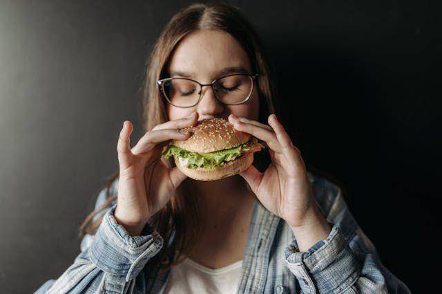 ilustrasi seseorang sedang makan junk food (pexels.com/Pavel Danilyuk)