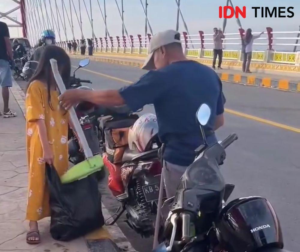 Pria dan anak perempuan sapu jembatan sungai sambas besar. (IDN Times/istimewa).