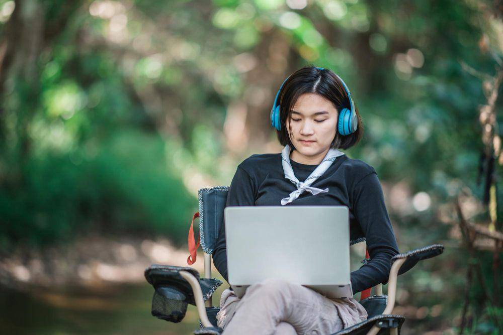 ilustrasi perempuan muda duduk di kursi roda sambil mendengarkan musik melalui headphone (freepik.com/jcomp)