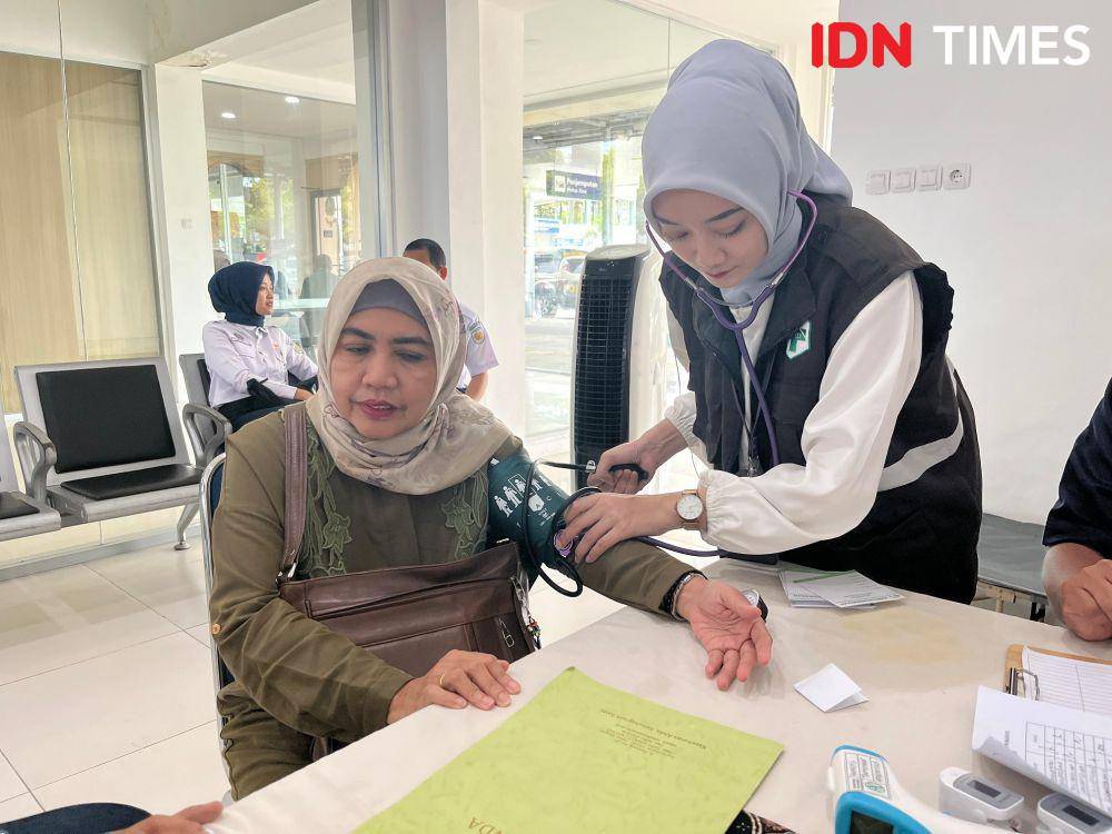 Petugas layanan kesehatan di stasiun Purwokerto (kanan) saat sedang memeriksa kondisi calon penumpang, Minggu (6/4/2025).(IDN Times/Cokie Sutrisno)