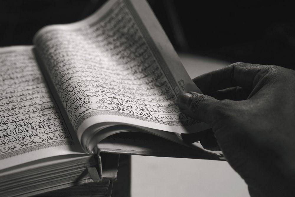 ilustrasi tangan seseorang yang sedang membuka lembaran Al Quran (pixabay.com/Joko_Narimo)