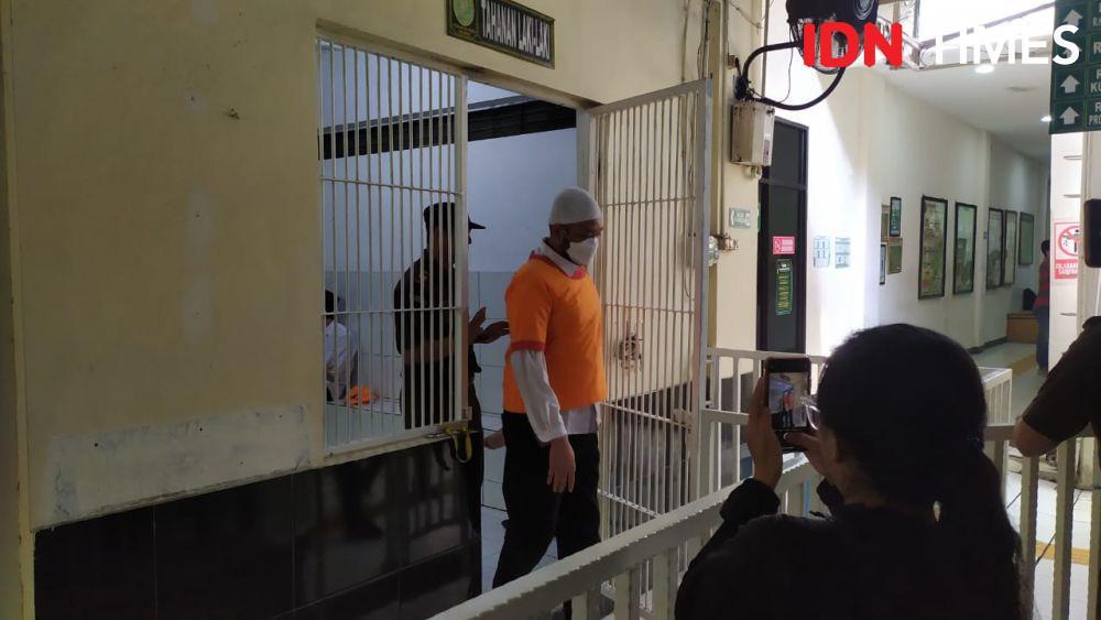 Terdakwa kasus penembakan GRO, Robig Zainudin keluar dari ruang tahanan menuju ruang sidang memakai kopiyah putih dan berbaju tahanan oranye. (IDN Times/Fariz Fardianto)
