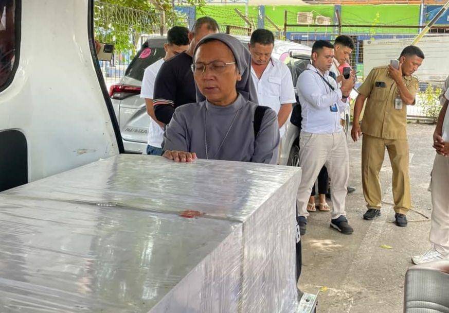 Seorang suster mendoakan jenazah PMI NTT yang dikirim dengan peti jenazah di pintu kargo Bandara El Tari Kupang. (Dok BP3MI NTT)