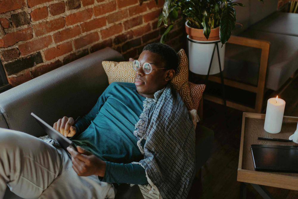 potret seorang pria rebahan memegang tablet (unsplash.com/Surface)