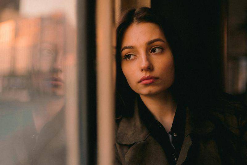 gambar seorang perempuan muda menatap ke luar jendela (pexels.com/Yura Forrat)