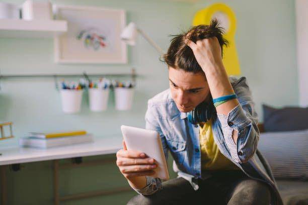 ilustrasi seorang remaja duduk di kamar, membuka media sosial dengan wajah cemas (istockphoto.com/Dejan_Dundjerski)