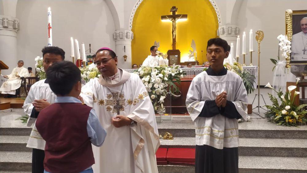 Bapa Uskup Agung Semarang Monsinyur Robertus Rubiyatmoko mengoleskan air suci pada bagian wajah seoranh jemaat anak di sela acara misa requeim di Katedral Semarang. (IDN Times/Fariz Fardianto)