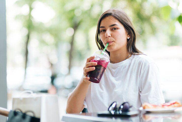 Ilustrasi segelas minuman manis berwarna cerah sebagai gambaran konsumsi minuman dengan kandungan gula tinggi.