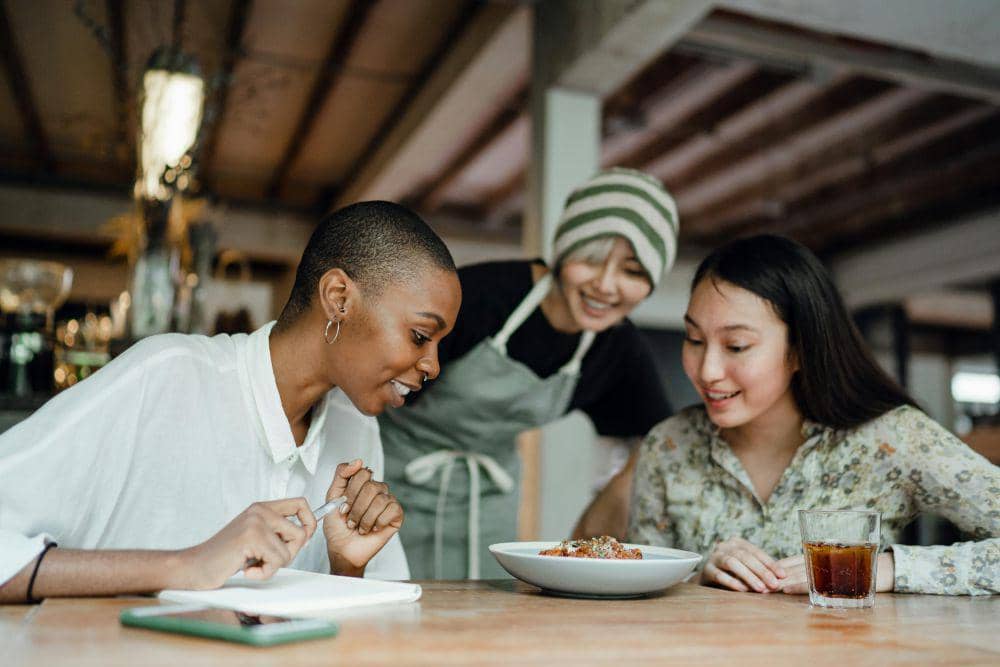ilustrasi pelanggan sedang terlihat me-review makanan dengan pelayan resto (pexels.com/Ketut Subiyanto)