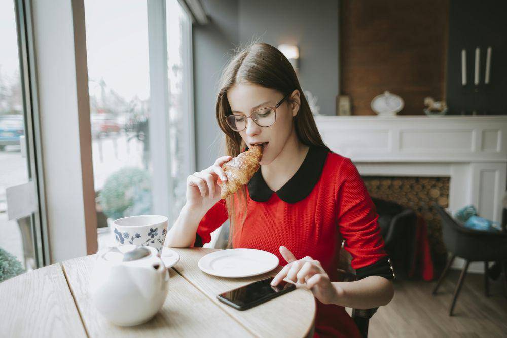 ilustrasi orang yang sedang makan sambil bermain hp(pexels.com/ Andrea Piacquadio)
