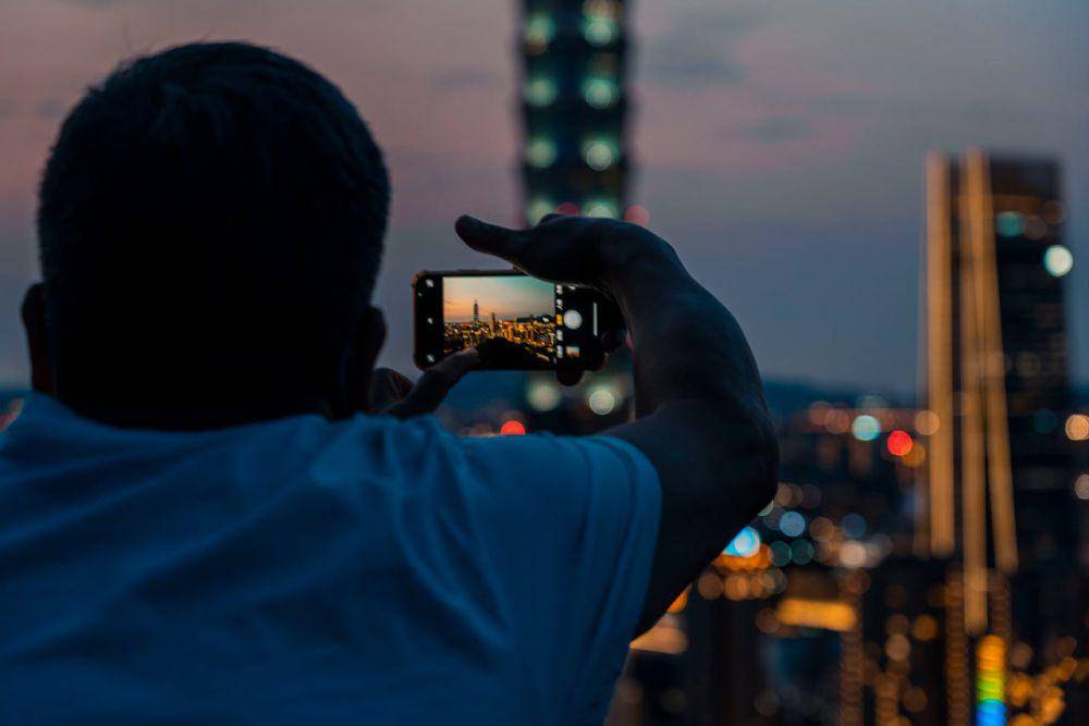 ilustrasi seseorang yang sedang mengambil foto pemandangan kota di malam hari (pexels.com/Jimmy Liao)