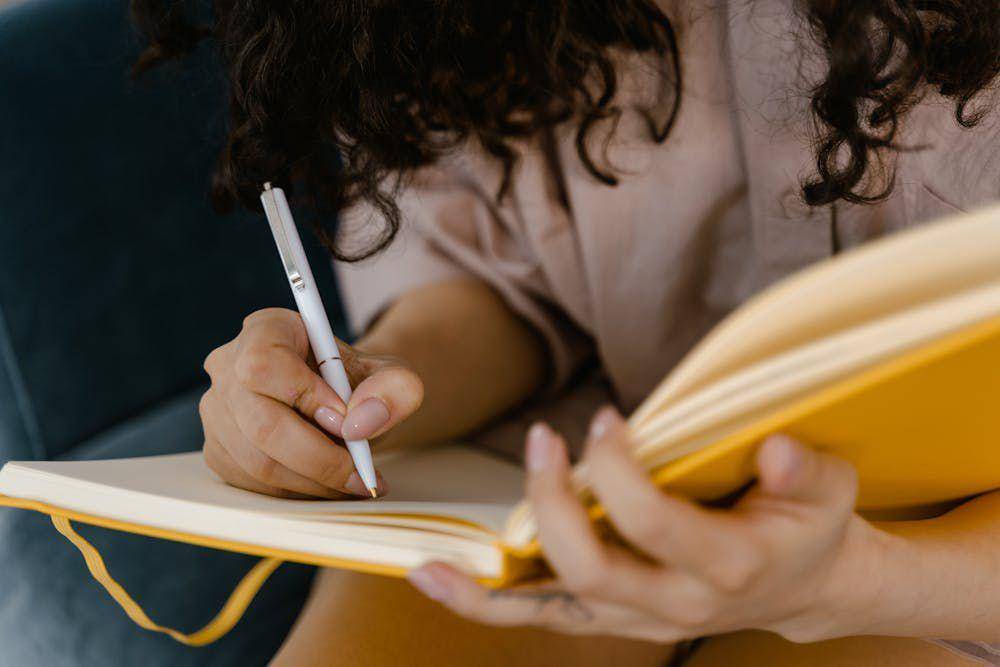 ilustrasi wanita sedang menulis jurnal (pexels.com/MART PRODUCTION)
