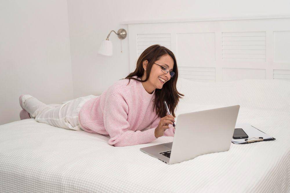 ilustrasi menggunakan laptop di atas kasur (freepik.com/freepik)
