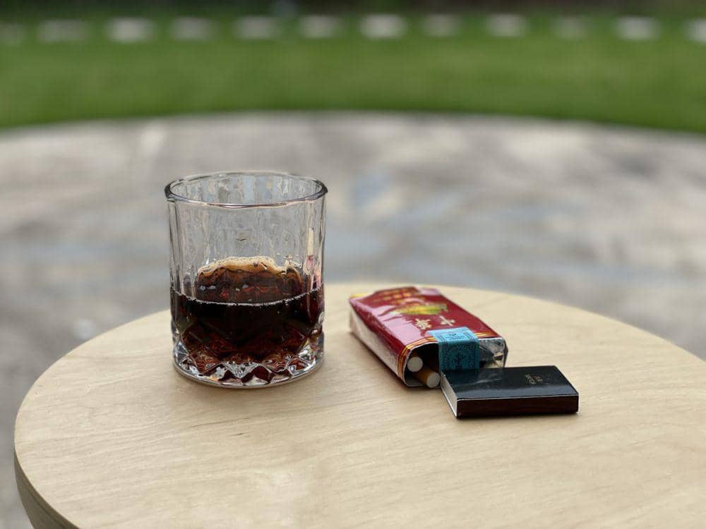 Rokok dan segelas minuman beralkohol di meja.