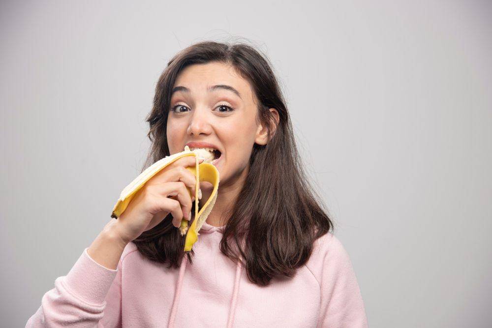 ilustrasi perempuan makan pisang (freepik.com/azerbaijan stockers)