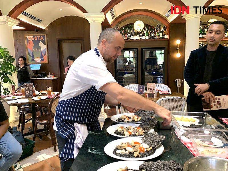 Potret Chef Tommaso menyajikan Black Ink Risotto di Osteria Gia Surabaya pada Selasa (20/5/2025) (IDN Times/Fasrinisyah Suryaningtyas)