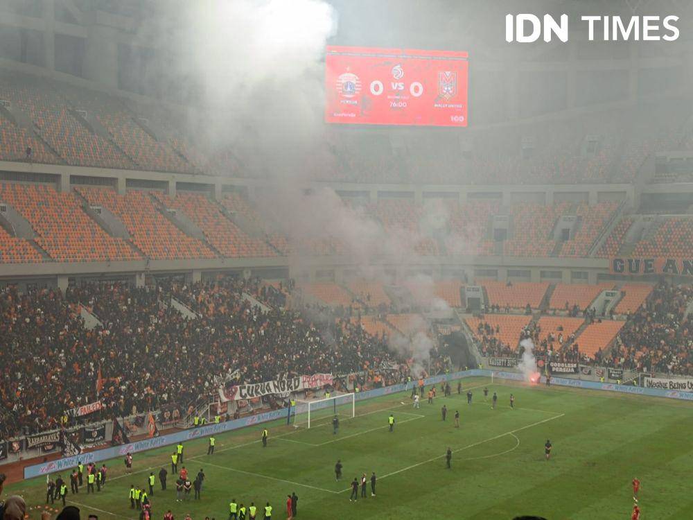 Suporter Persija, Jakmania menyalakan flare dan membuat duel timnya lawan Malut United di laga terakhir Liga 1 2024/25 dihentikan. (IDN Times/Tino)