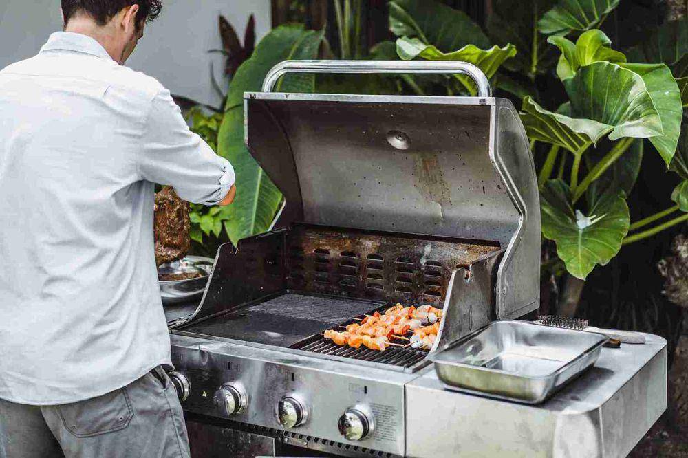 Ilustrasi Grill (Freepik.com/A man in tattoos makes barbecue grill meat outdoors.)