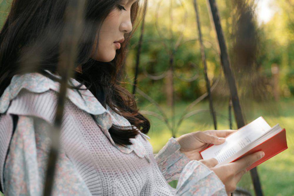ilustrasi wanita membaca buku di taman (pexels.com/Mikhail Nilov)