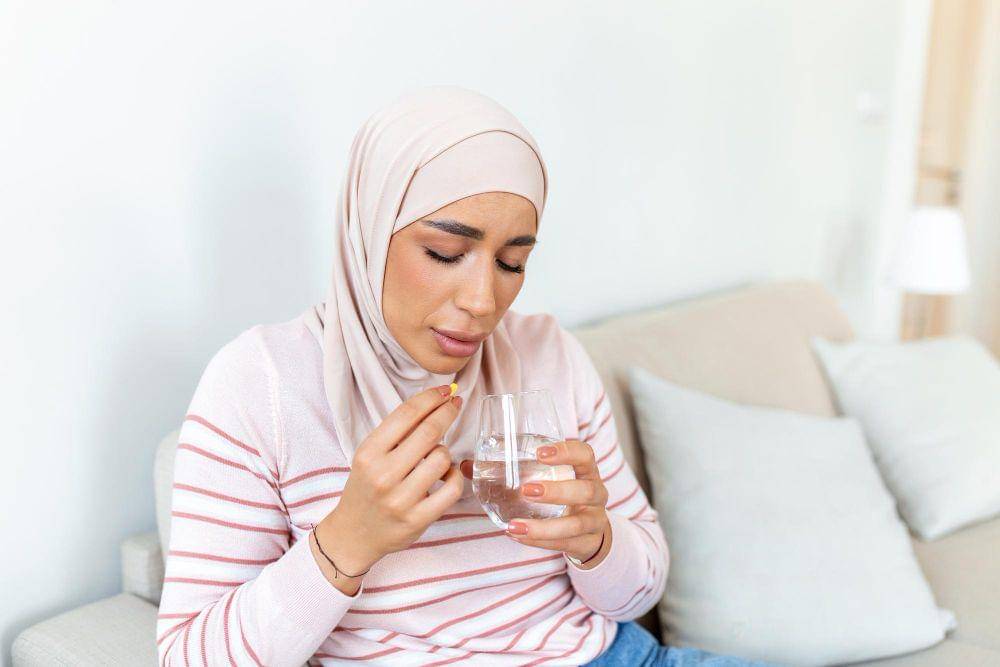 Seorang perempuan mengonsumsi suplemen zat besi.