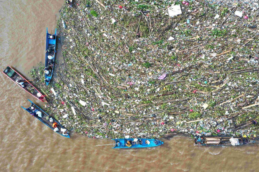 Warga menggunakan perahu ketinting mengambil sampah yang berada di aliran muara Sungai Karang Mumus di Samarinda, Kalimantan Timur, Sabtu (31/5/2025). ANTARA FOTO/M Risyal Hidayat/agr
