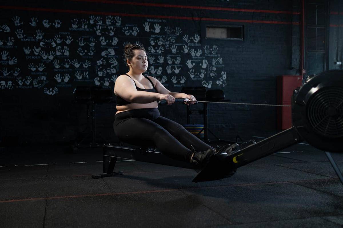 Seorang perempuan menggunakan rowing machine.