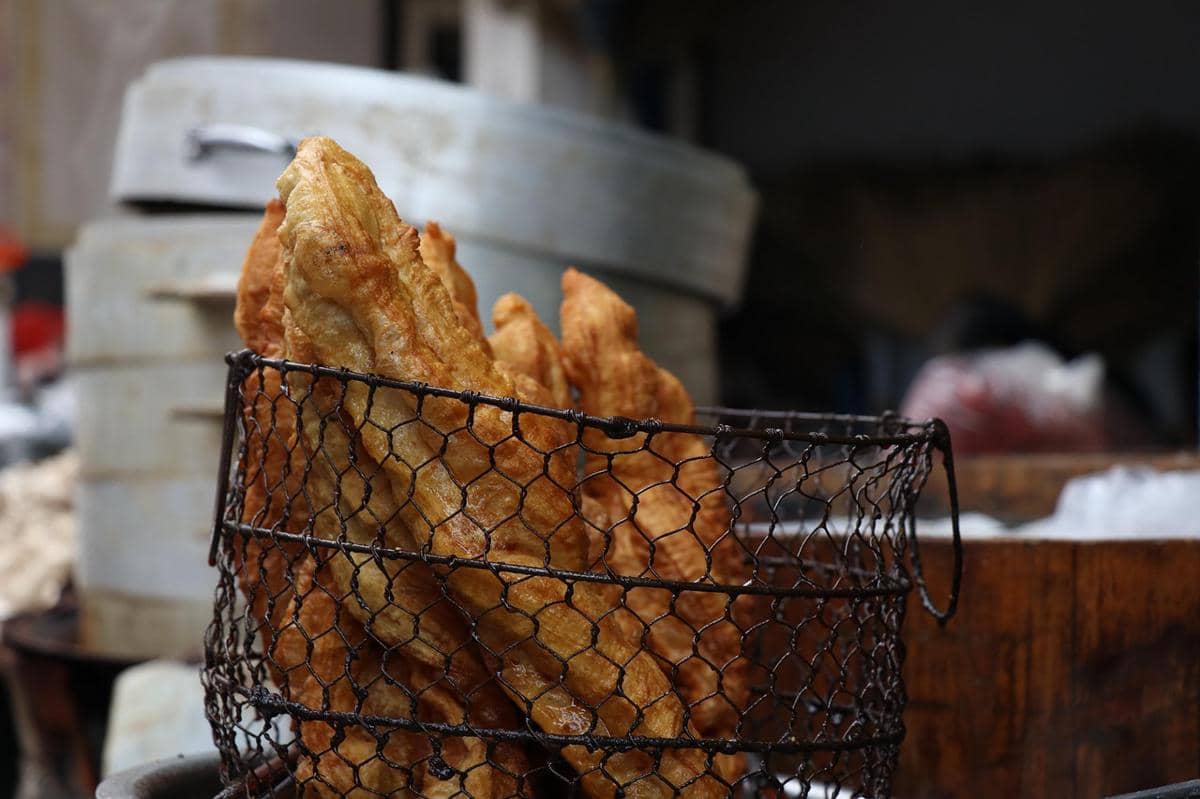 Ilustrasi cakwe goreng berwarna cokelat keemasan yang disajikan sebagai hidangan sarapan di atas piring.