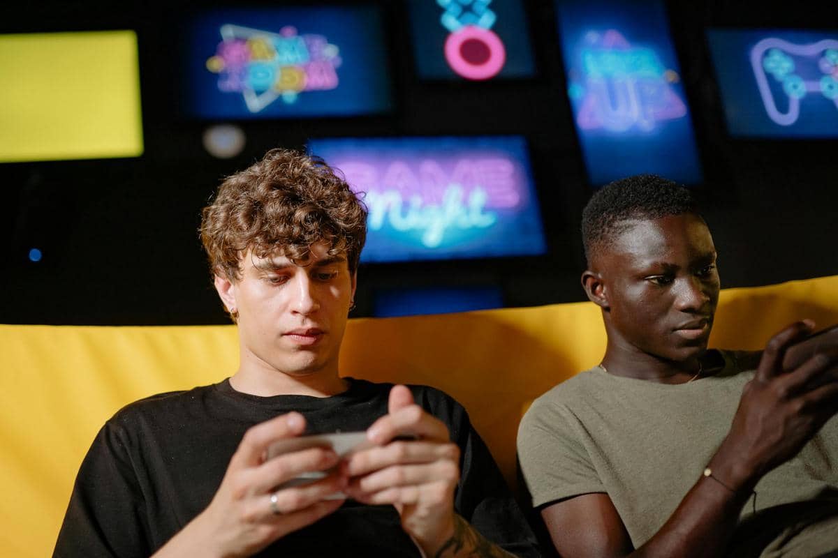 Dua remaja sedang bermain game dengan serius, ilustrasi HP panas dan lemot saat digunakan. Sumber: Pexels.com / cottonbro studio