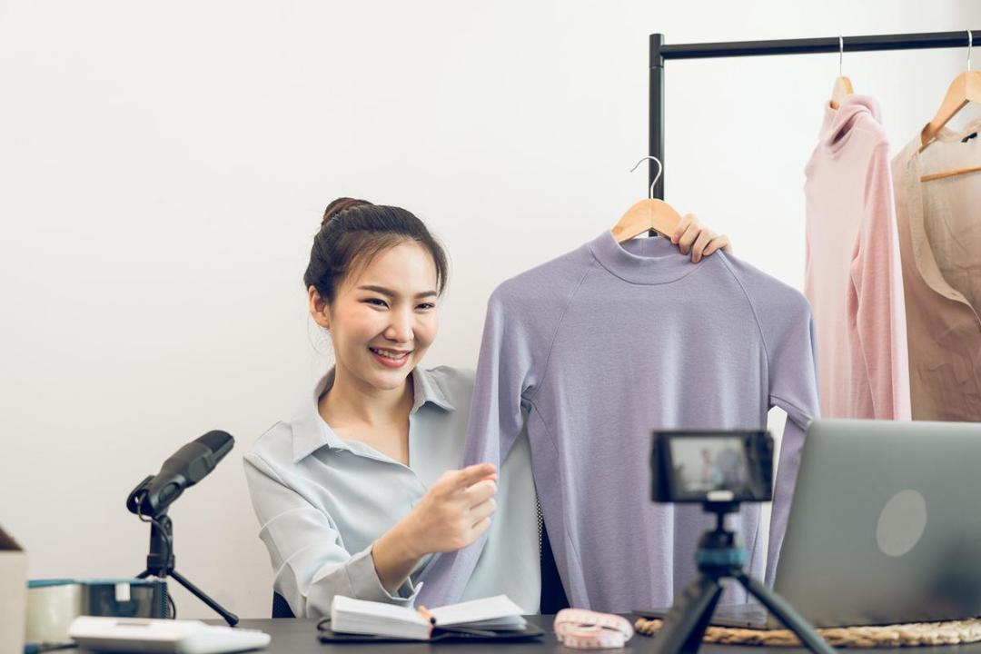 Ilustrasi seorang perempuan melakukan live shopping menjual baju