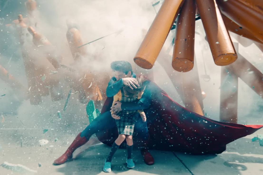 Di tengah kekacauan, Superman menunjukkan sisi heroiknya dengan memeluk dan melindungi seorang anak dari bahaya. (dok. DC/Superman | Official Trailer | DC)