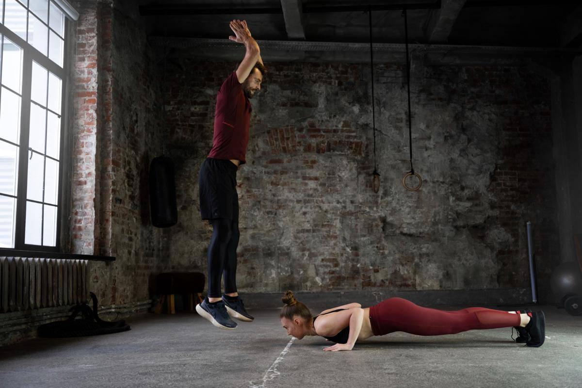 Seorang laki-laki dan perempuan melakukan gerakan burpees.