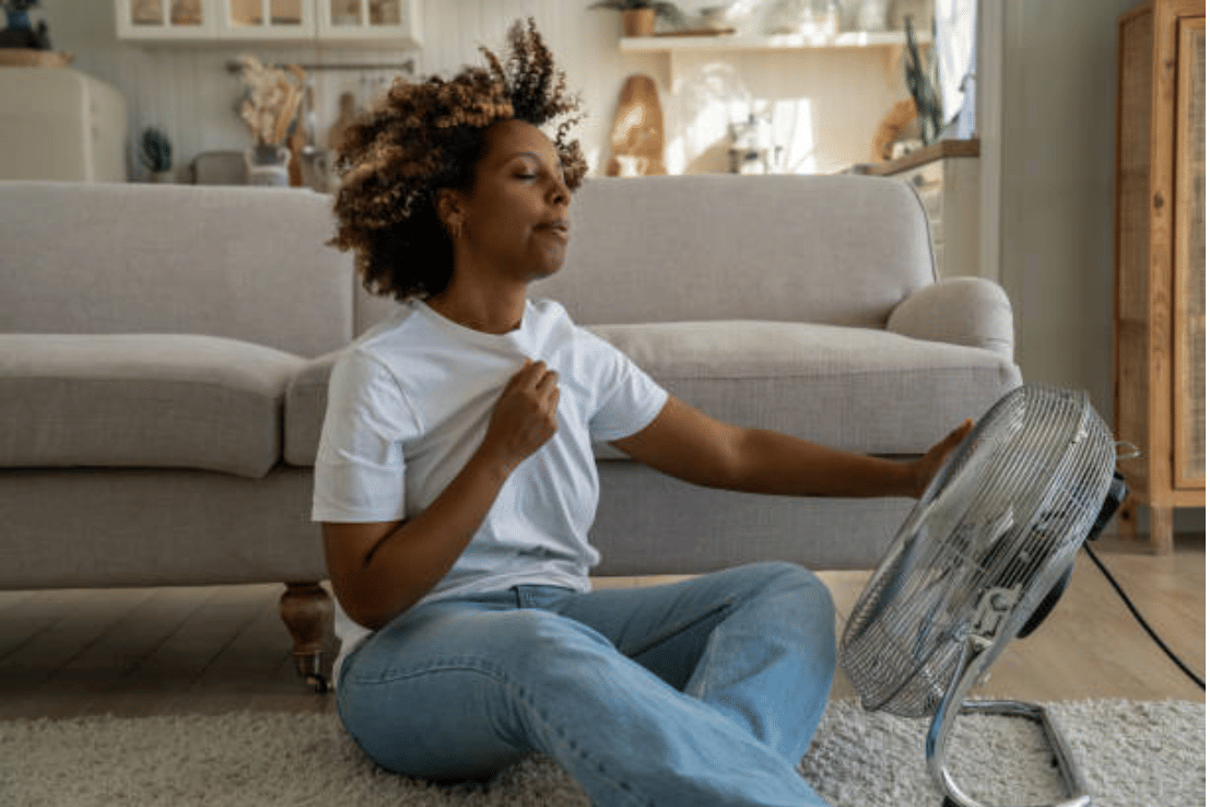 Wanita muda Afrika-Amerika mendinginkan diri dengan ventilator di rumah, merasa tidak enak badan selama gelombang panas. (istockphoto.com/Dima Berlin)