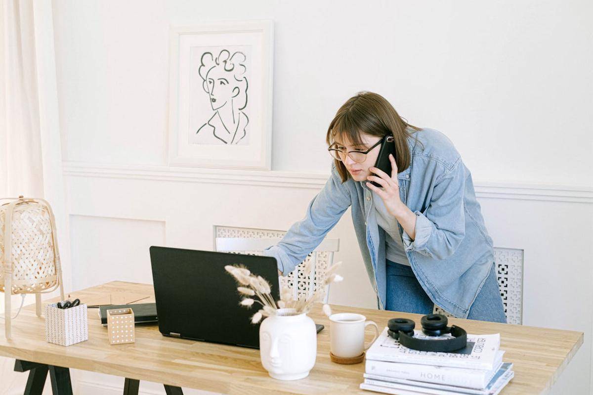ilusrasi perempuan sedang menatap laptop sambil menelepon (pexels.com/Ivan Samkov)