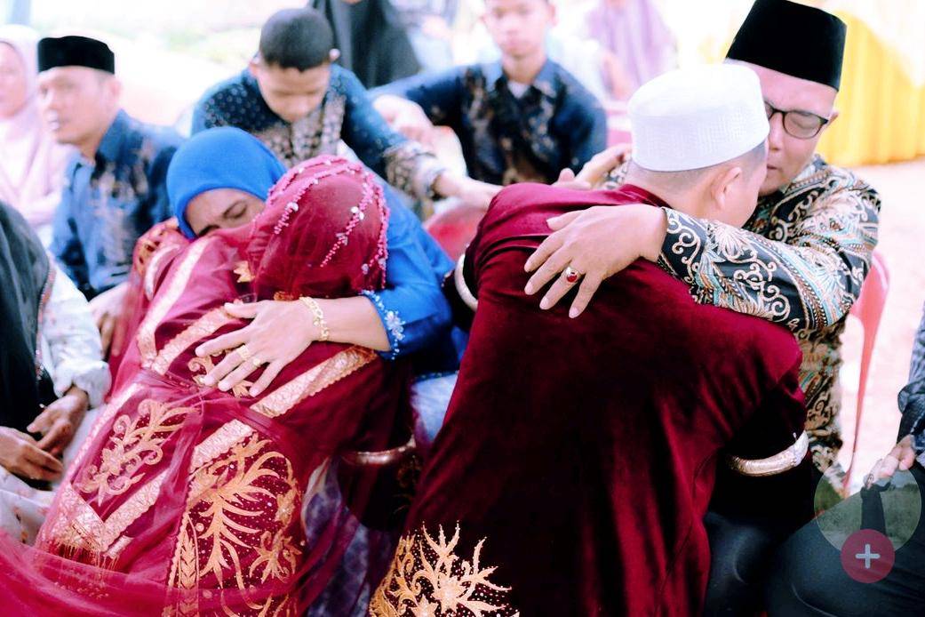 Kedua mempelai yang mengenakan busana adat merah dengan hiasan keemasan bersujud dan memeluk orang tua mereka sebagai simbol penghormatan, permohonan doa restu, dan permohonan maaf.(tiktok.com/rinisiregarr1)