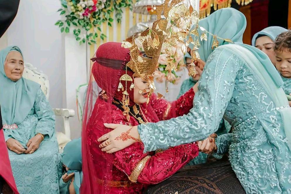pengantin wanita mengenakan bulang-bulang dan busana adat bersimpuh serta memeluk kerabat perempuan untuk meminta doa restu. Tradisi ini menjadi simbol bakti, penghormatan, serta permohonan izin memulai rumah tangga baru.(tiktok.com/sasiah_22)