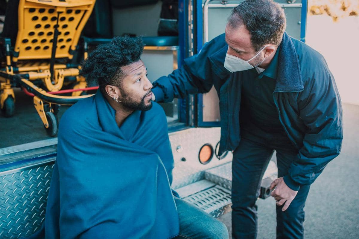 Ilustrasi petugas paramedis menenangkan seseorang pasca kejang epilepsi.