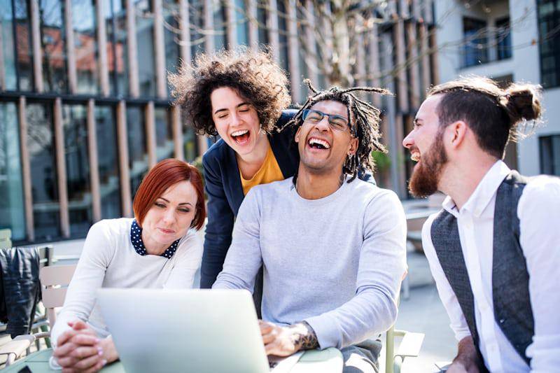 Pengusaha muda dengan laptop di luar ruangan di halaman, tertawa (unsplash.com/Getty Images)