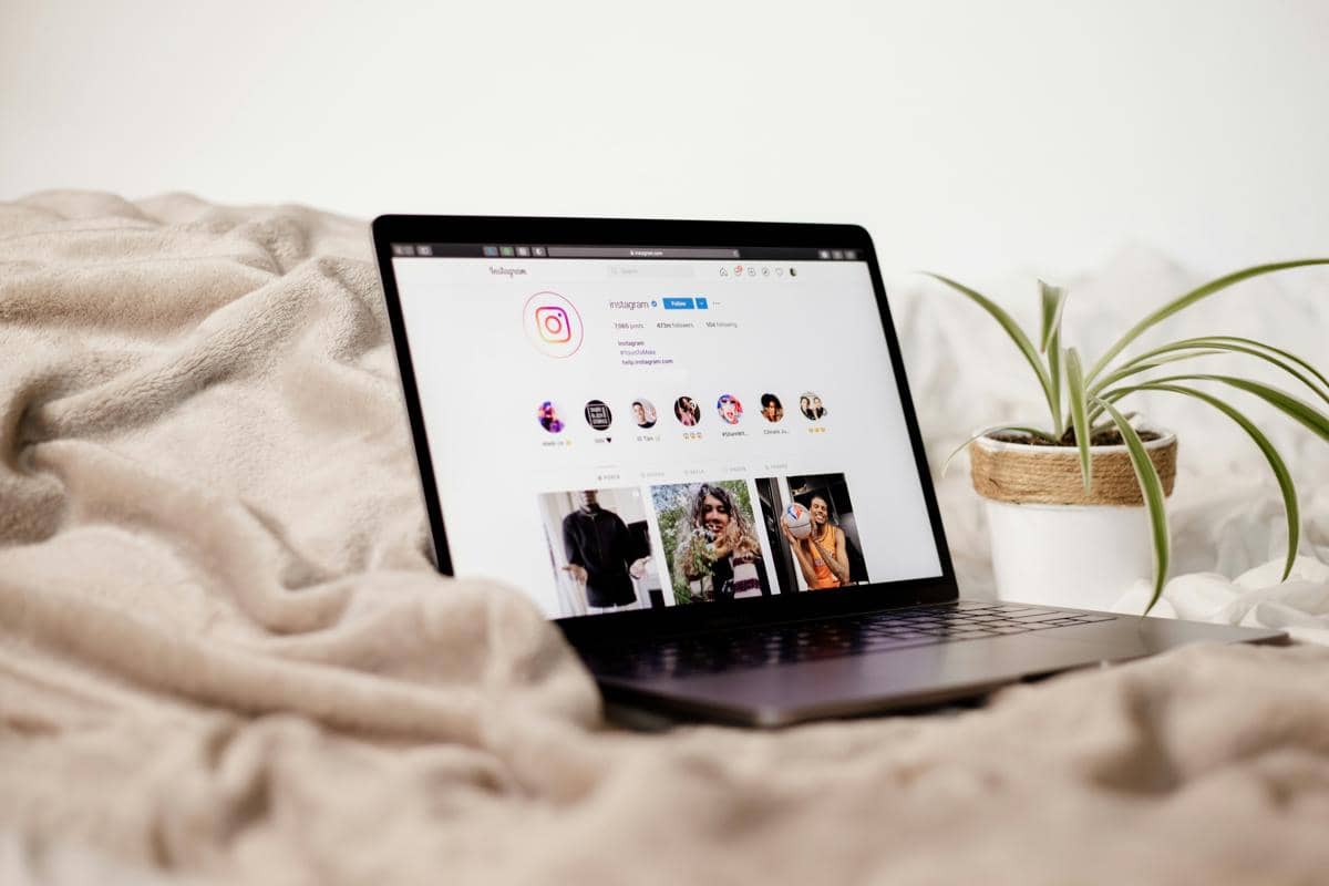 Laptop diatas tempat tidur menampilkan laman instagram (unsplash.com/Collabstr)