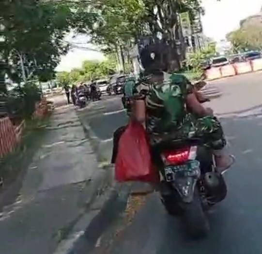 Dua pria berbaju loreng mengendarai sepeda motor di Makassar tidak ditilang saat melintas di depan razia polisi, Rabu (6/8/2025).
