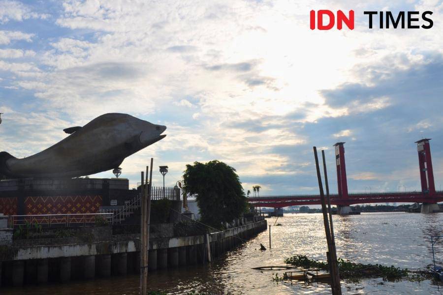 Tugu Iwak Belido berlatarbelakang Jembatan Ampera Palembang