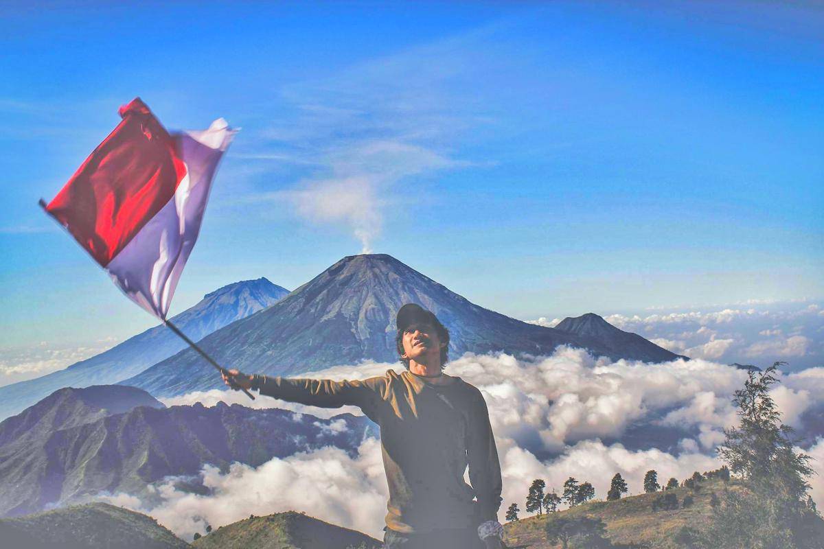 ilustrasi mengibarkan bendera Indonesia saat hiking (pexels.com/Dio Hasbi Saniskoro)