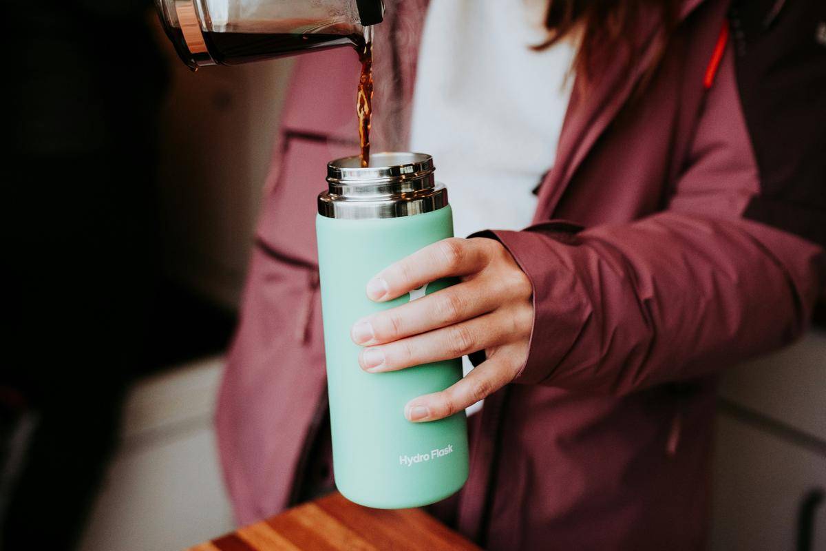 ilustrasi orang sedang menuang minuman ke dalam botol insulated (unsplash/Negley Stockman)