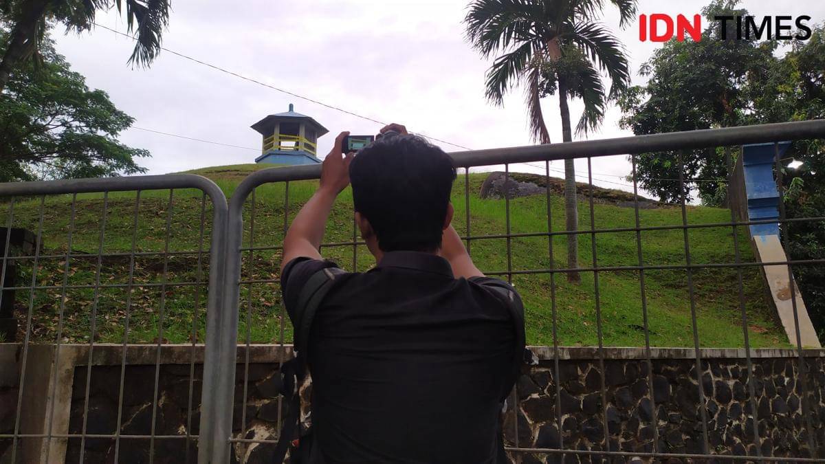 Seorang wartawan televisi mengambil gambar pucuk bangunan Reservoir Siranda yang telah ditutup garis polisi. (IDN Times/Fariz Fardianto)